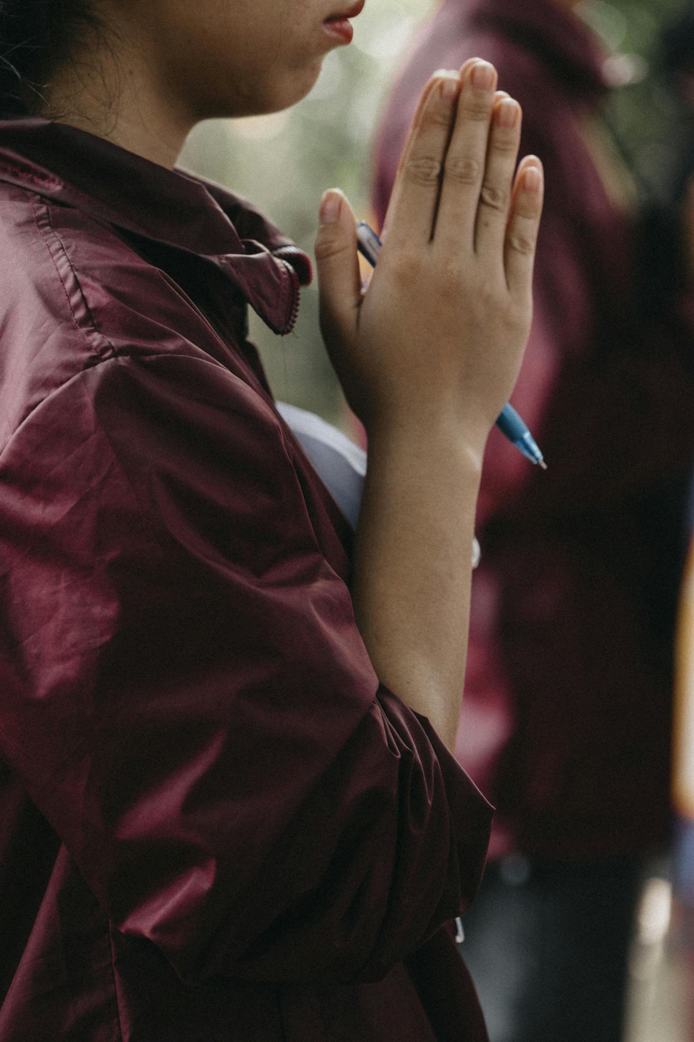 Side profile of a person meditating with hands in prayer outdoors, relaxation and mindfulness
